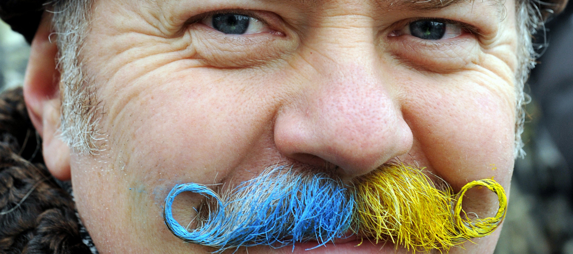 A man with a mustache painted in the colors of the Ukrainian flag poses for a photograph in Independence Square in Kiev during a mass opposition rally on December 15, 2013. At least 200,000 pro-European demonstrators began a mass rally in the Ukrainian capital today in a fresh show of force against President Viktor Yanukovych after his failure to sign a key EU agreement. AFP PHOTO / YURIY DYACHYSHYN